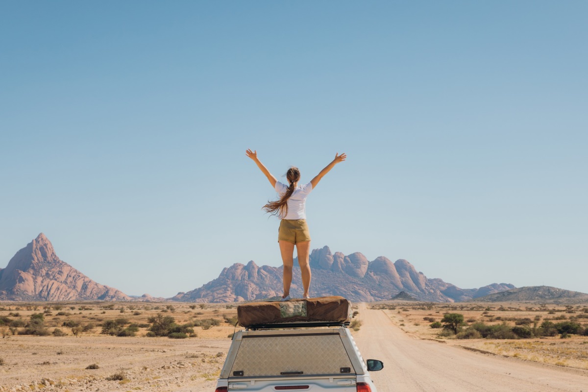A woman stands on top of her 4x4 in Namibia.