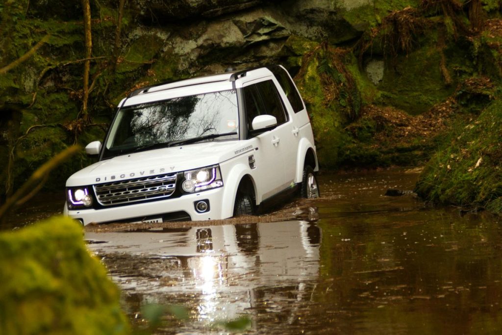 A Land Rover Discovery driving through water.