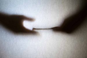 Silhouette of business man hands giving bribe isolated on grey background.