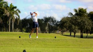 A golfer swinging his club on a golf course.
