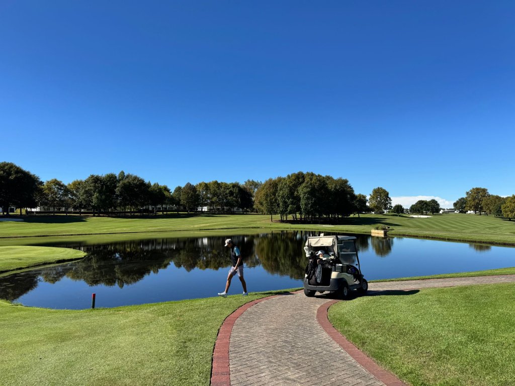 A golfer walking on the green fairway.