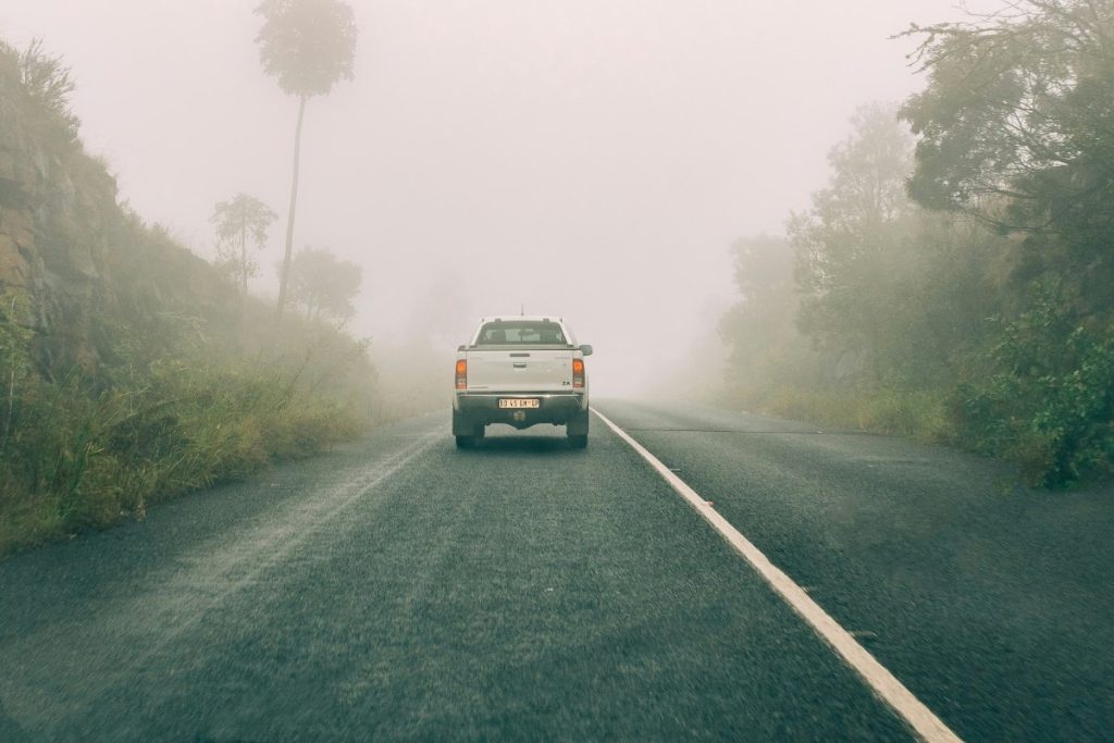 A bakkie (pick-up truck) drives along a misty road in South Africa.