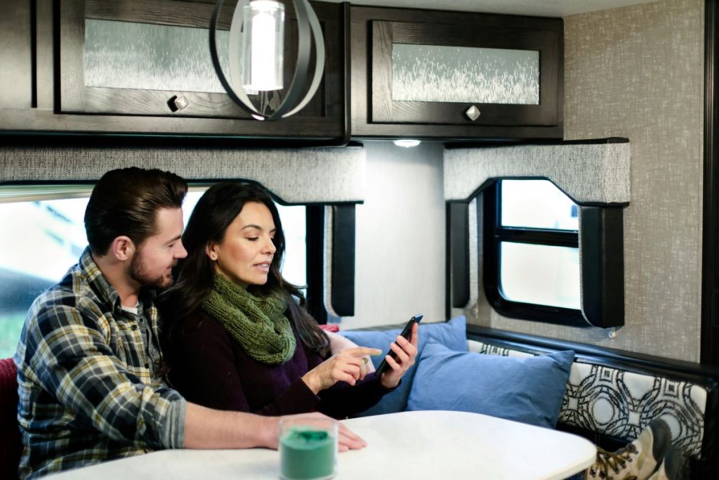 A young couple using a phone in an RV.