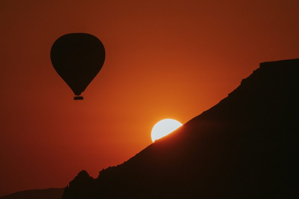 A hot air balloon over a mountain at sunrise.