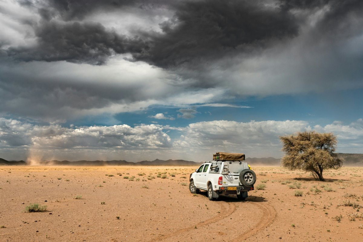 A 4x4 hire vehicle drives through the Namibian desert landscape.
