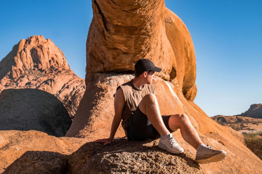 A man sits down as he hikes Spitzkoppe in Namibia