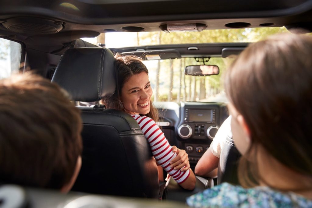 A mother smiles at her children in the car.