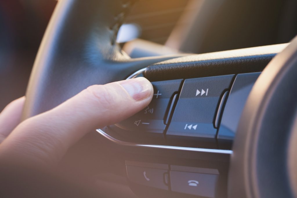 A person changes the volume on a car steering wheel.