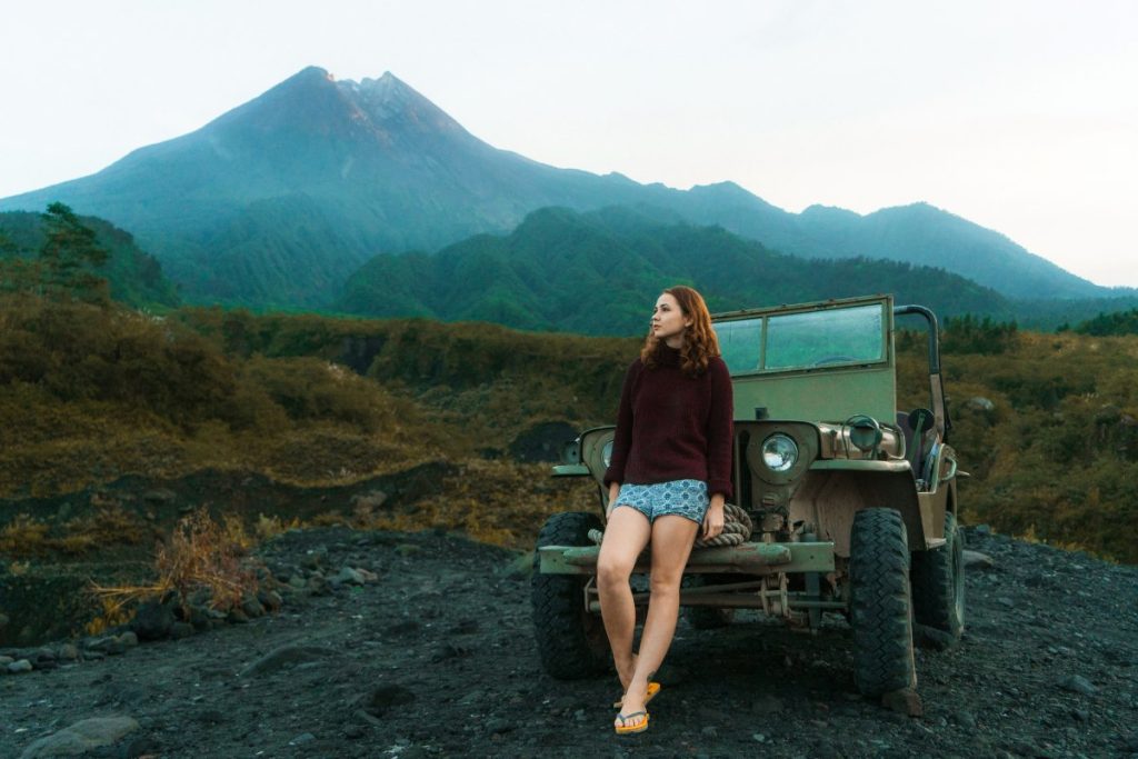 A woman stands in front of a Willys Jeep.