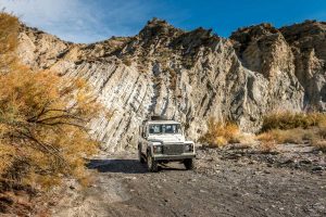 A Land Rover against a rocky backdrop.