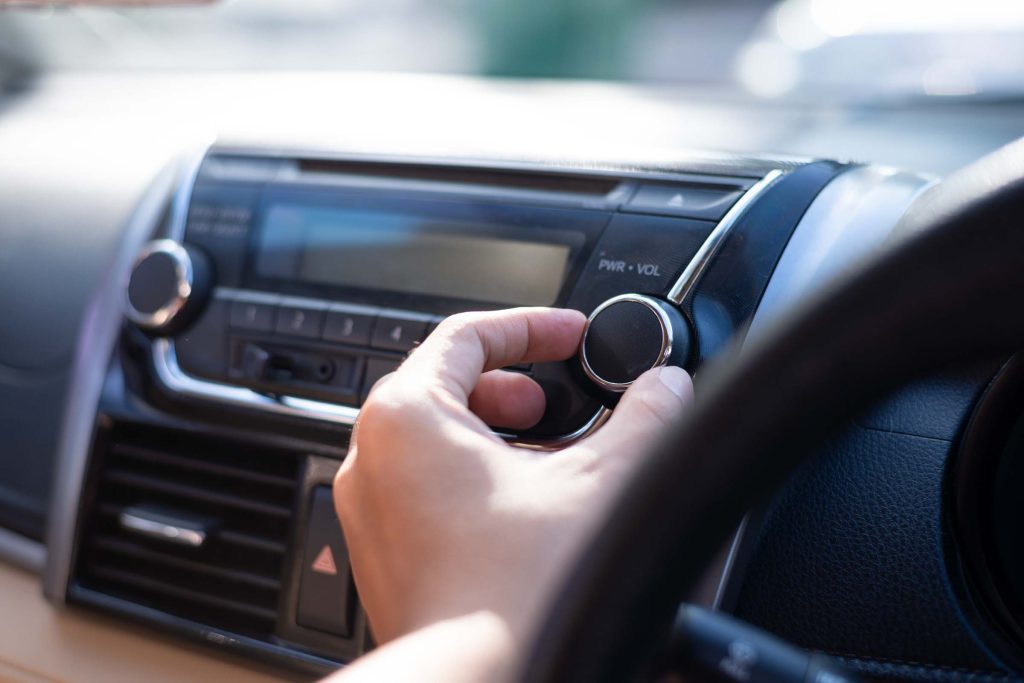 Man is using radio and control volume in the car.