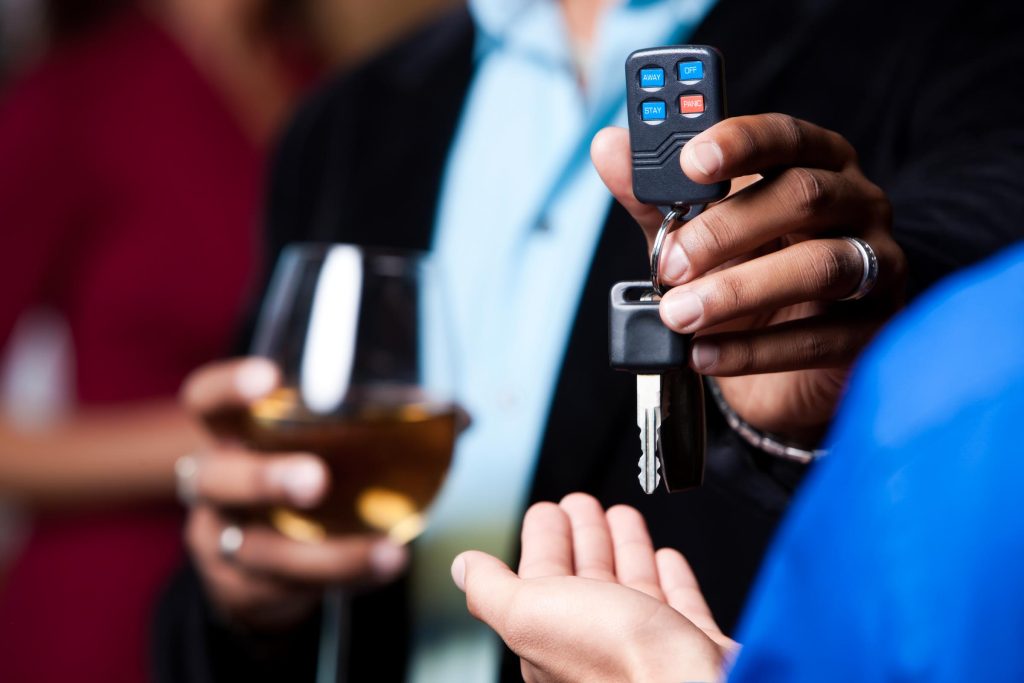 A man who is drinking gives his car keys to a friend.