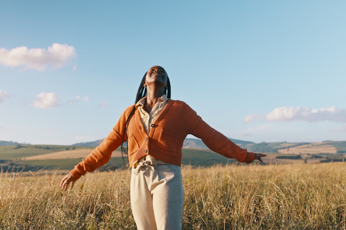 A woman stands in a field of grass.