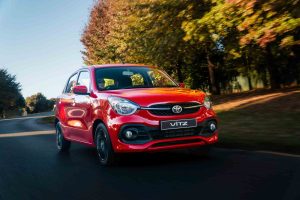 A red Toyota Vitz on the road.