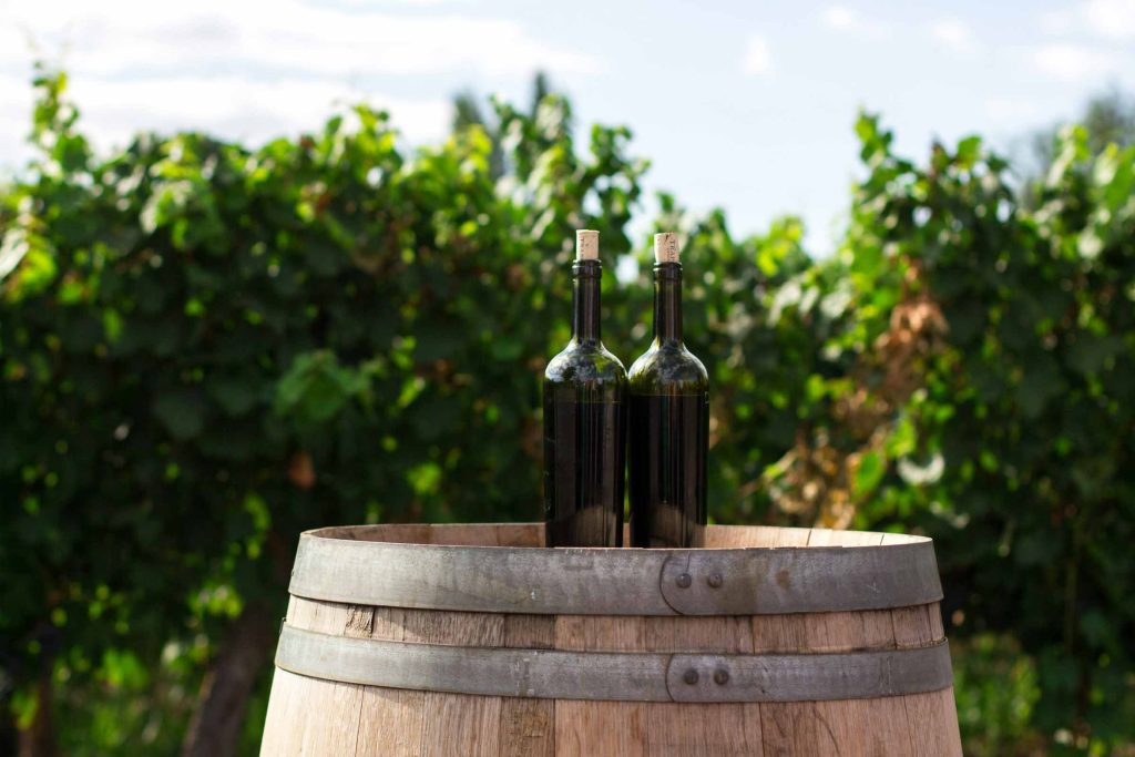 Two bottles of wine on a barrel.