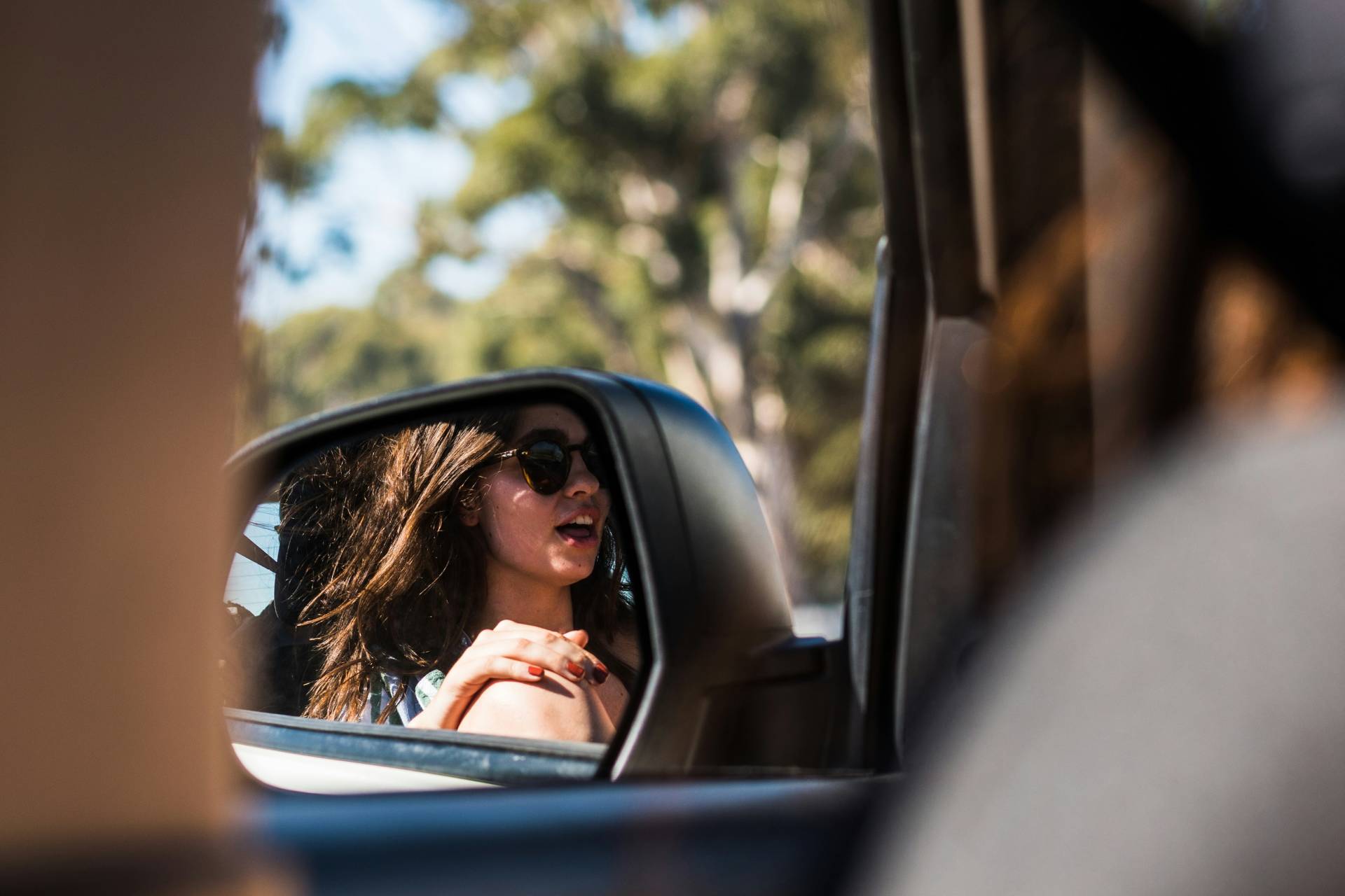 Reflection of a woman in the sideview mirror of a car