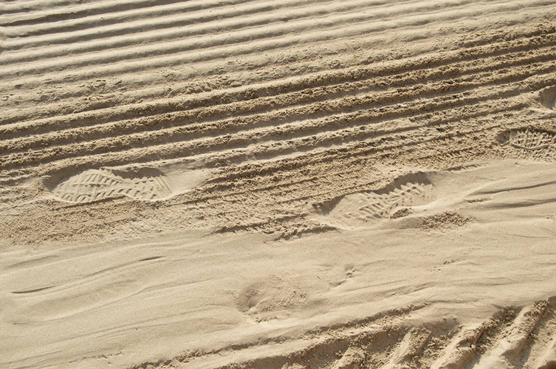 Close up of a sandy road with tiretracks and footprints