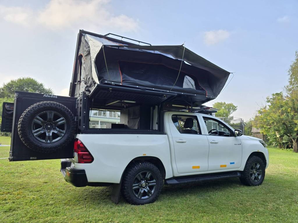 4x4 safari vehicle with an opened rooftop tent at a campground