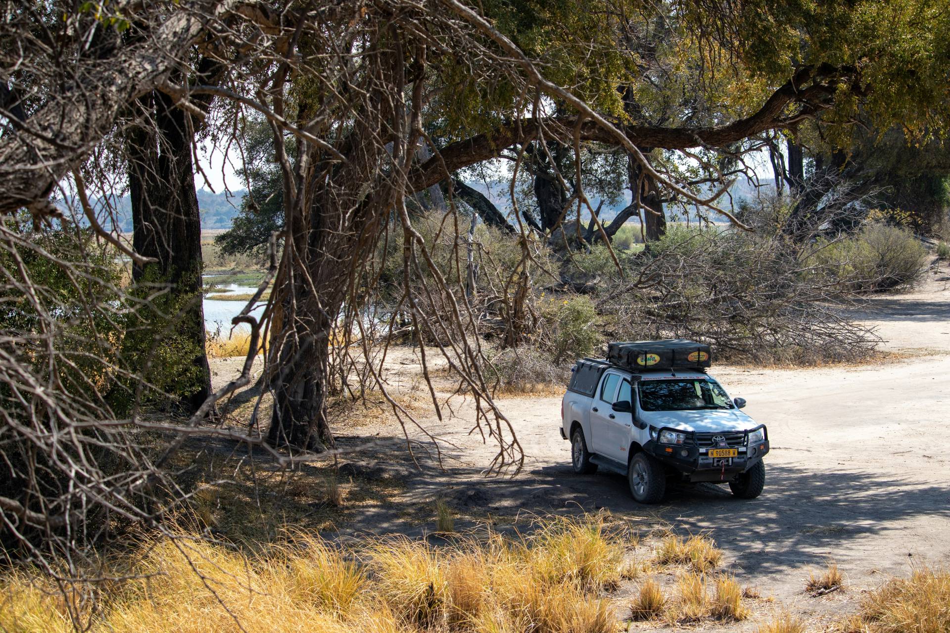 A 4x4 vehicle parked in the shade under a tree.