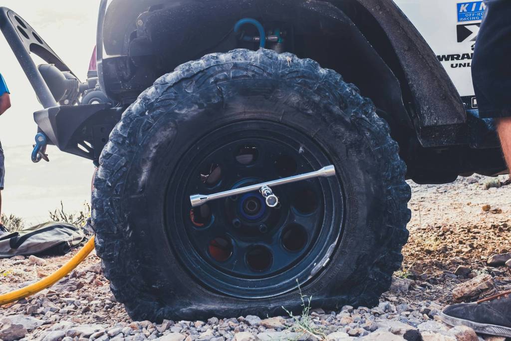 A flat tyre on a 4x4 vehicle on a gravel road.