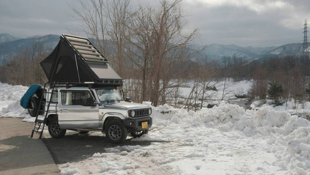 An equipped 4x4 parked in the snow with a rooftop tent.