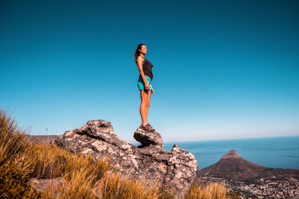 A woman standing on a cliff with Lions Head in the distance, Cape Town.